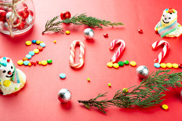 2022 festive background made of candy canes and chocolate buttons, sweet snowmen