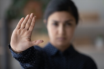 Close up focus on hand of serious young Indian woman showing stop gesture to camera, protesting against racial or sexual discrimination or abuse, domestic violence, bullying attacks, discrimination.