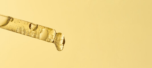 Closeup photography of the pipette with dripping oil.Zero waste wooden cover,warm yellow background.Cosmetics mockup concept.Large banner.