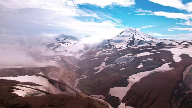 Magical aerial shot in Iceland approaching snow covered mountains with fog and steam from hot springs below. Epic view shot in highlands.