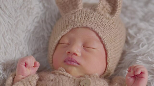 happy newborn baby weaing cute rabbit costume lying sleep on grey carpet background comfortable and safety.Cute Asian infant sleeping and napping on baby bed.Newborn Baby Easter Day Concept