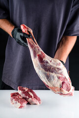 Male butcher holds in his hands raw meat lamb leg flesh. paleo diet, organic food.