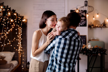 Young family playing with children in room decorated for christmas