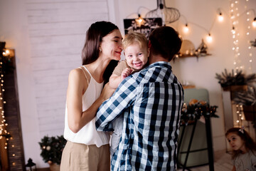 Young family playing with children in room decorated for christmas