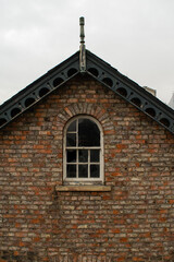 Fototapeta na wymiar Old broken window at roof of a traditional British brick house