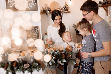 Beautiful family preparing homemade cakes on the christmas table against the backdrop of the decorations for the holiday