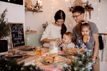 Beautiful family preparing homemade cakes on the christmas table against the backdrop of the decorations for the holiday