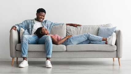 African american couple spending weekend together lying on couch - Powered by Adobe