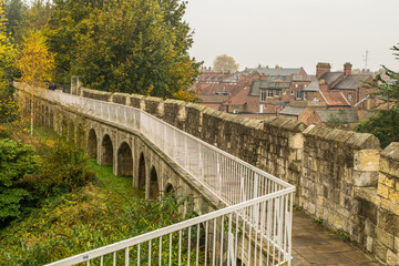 Arches under the trail on top of medieval 13th century city wall with view of the town of York in England