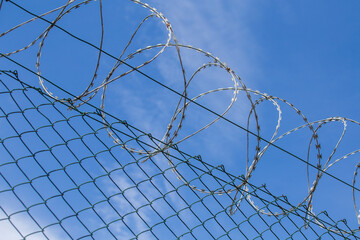 Chain link fence with barbed wire under blue sky
