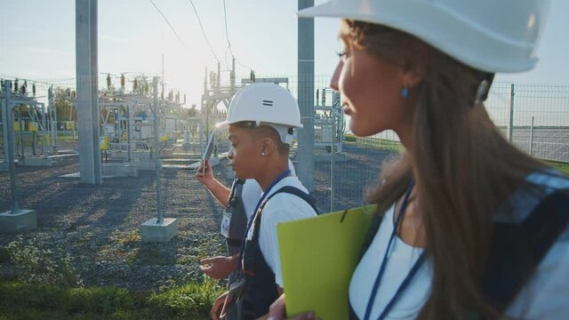 Professional group of civil engineers walking on solar station construction. Male and female multiethnic workers talking and working together. Solar farm. Business team.