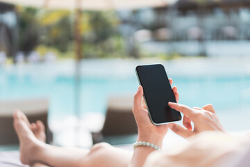 Woman using smartphone and sitting on bed at swimming pool resort abstract background. Technology...