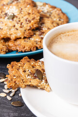 Cup of coffee with milk and fresh baked oatmeal cookies with honey and healthy seeds. Delicious crunchy dessert