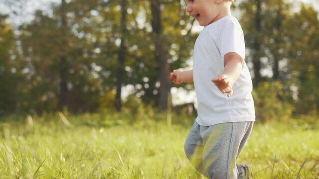 Baby Run The First Steps. Kid Running In Nature On The Grass In Park Silhouette. Happy Family Kid Dream Concept. People In Lifestyle The Park. Baby Run, Outdoor Fitness Forest. Happy Family Catch-up