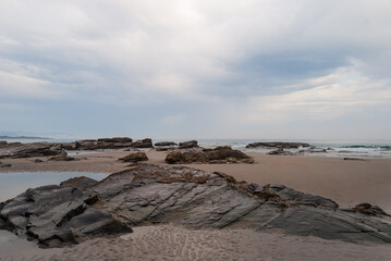 Rocks between the sand on the beach of the cathedrals of Galicia