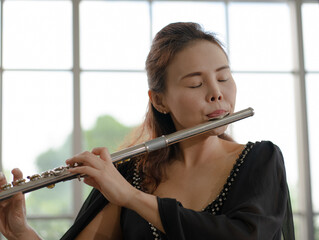 portrait of musician woman playing flute in room © plo