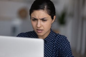 Unhappy stressed nervous young Indian ethnicity woman looking at laptop screen, feeling confused of getting bank loan rejection, dismissal notice by email or reading notification with bad news.