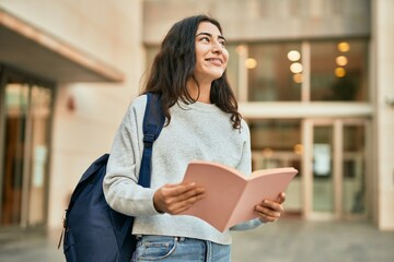 Young middle east student girl smiling happy reading book at the city.