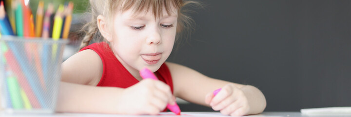 Little girl drawing picture with colored pencils at home