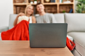 Young caucasian couple smiling happy watching movie eating popcorn at home.