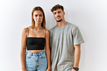 Naklejka premium Young beautiful couple standing together over isolated background depressed and worry for distress, crying angry and afraid. sad expression.