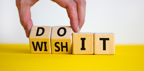 Wish and do it symbol. Businessman turns cubes and changes words 'wish it' to 'do it'. Beautiful yellow table, white background. Business and wish and do it concept. Copy space.