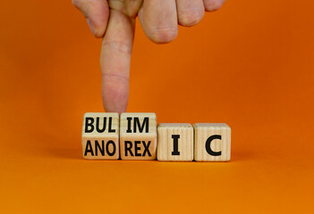 Bulimic or anorexic symbol. Doctor turns wooden cubes and changes the word anorexic to bulimic. Beautiful orange table, orange background, copy space. Medical, bulimic or anorexic concept.