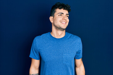 Fototapeta premium Young hispanic man wearing casual clothes looking to side, relax profile pose with natural face and confident smile.