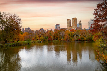 Skyline reflected in water in Central Park, NYC, surrounded by brilliant fall foliage