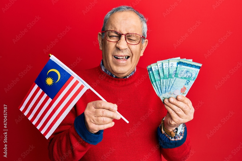 Canvas Prints handsome senior man with grey hair holding malaysia flag and malaysian ringgit banknotes winking loo