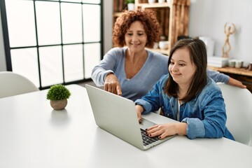 Mature mother and down syndrome daughter using computer laptop at home
