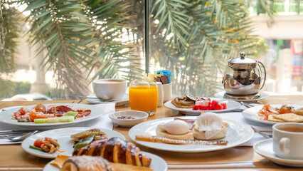 Breakfast in luxury hotel. Table full of various food from buffet in modern tropical resort. Morning food - fresh bakery, glasses of orange juice, eggs, plate with tropical fruits in restaurant