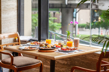 Breakfast in luxury hotel. Table full of various food from buffet in modern city resort. Morning food - fresh bakery, glasses of orange juice, eggs and plate with tropical fruits in restaurant