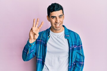 Naklejka premium Handsome hispanic man wearing casual clothes showing and pointing up with fingers number three while smiling confident and happy.