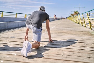 Middle age hispanic man wearing sportswear ready to run at street
