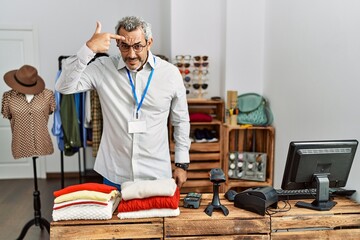 Middle age hispanic man working as manager at retail boutique pointing unhappy to pimple on forehead, ugly infection of blackhead. acne and skin problem