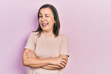 Obraz premium Middle age hispanic woman with arms crossed gesture winking looking at the camera with sexy expression, cheerful and happy face.