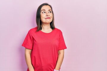 Middle age hispanic woman wearing casual clothes smiling looking to the side and staring away thinking.