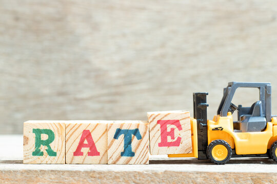 Toy forklift hold letter block t to complete word rate on wood background