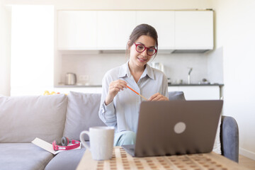 Pretty  woman teacher coach in glasses holding online lesson. Focused positive female student in eyeglasses looking at laptop screen, studying, watching webinar training, listening to lecture.