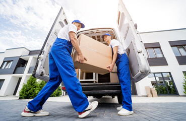 Two removal company workers unloading boxes and furniture from minibus