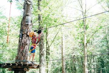 Boy attaches belt to safety rope to zip line between trees