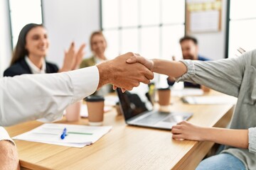 Group of business workers smiling and clapping to partners handshake at the office.