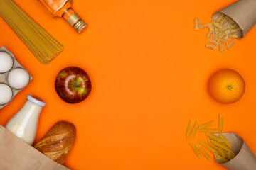 Bread and bottle of milk in paper eco bag. Spaghetti, sunflower oil, eggs and red apple