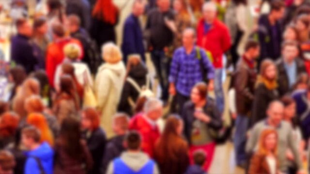 Crowd of people visiting the exhibition in bright demi-season clothes walk through the spacious halls of the mall pavilion.