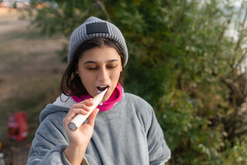 Young woman brushing her teeth with an electric brush in nature