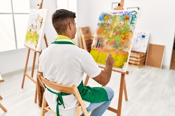 Fototapeta premium Young hispanic man on back view drawing at art studio