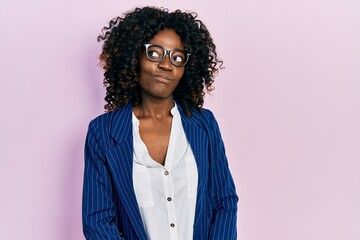 Young african american woman wearing business clothes and glasses smiling looking to the side and...