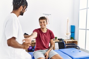 Two men physiptherapist and patient having rehab session stretching arm at clinic