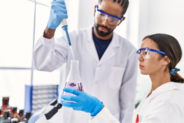 Man and woman scientist partners working using test tube and pipette at laboratory